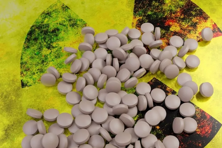 Iodine pill on yellow black radiation sign. Potassium iodide, KI or stable iodine tablet for nuclear accident protection. 3d render<br>jod, kalijev jodid, zračenje, radioaktivno, radijacija, nuklearni rat, nuklearni napad, lijek, tablete joda