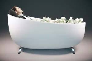 Handsome relaxing businessman lying in bathtub filled with dollar banknotes on grey background. Success concept. 3D Rendering