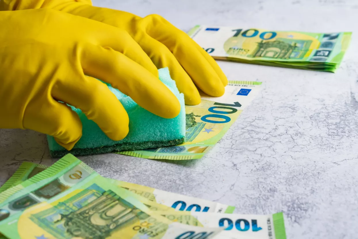 Pranje novca - ilustracija<br>Laundering of money. Man in yellow gloves washes papper hundred 100 euro with green washcloth
