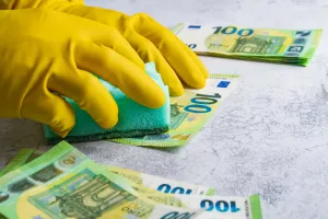 Pranje novca - ilustracija<br>Laundering of money. Man in yellow gloves washes papper hundred 100 euro with green washcloth