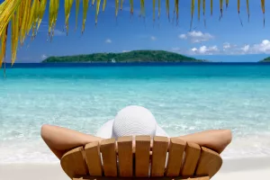 woman sunbathing in a teak chair on a beautiful Caribbean beach