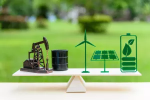 Fossil fuel vs renewable/future clean alternative energy concept: Petroleum pumpjack, crude oil drum barrel, solar panel, green leaf battery, wind turbine on a wood balance scale in equal position.<br>fosilna goriva, nafta, plin, zelena energija, zelena tranzicija, obnovljivi izvori energije