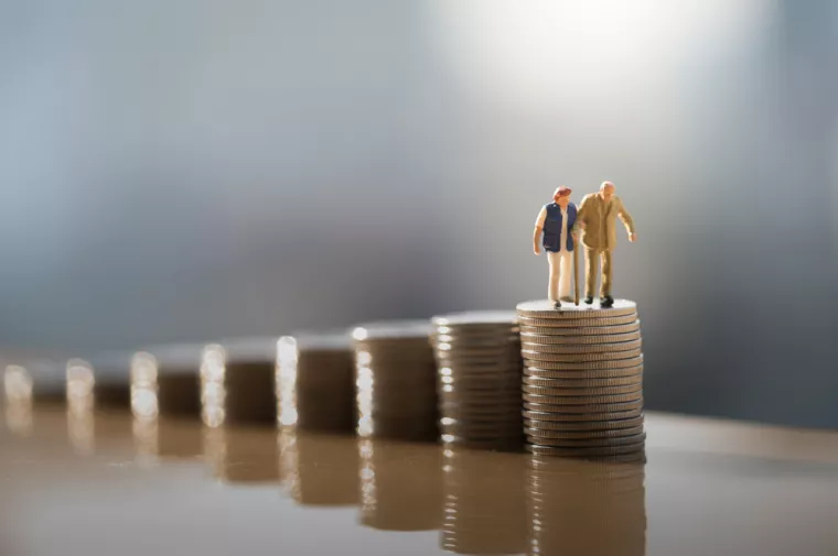 Concept of retirement planning. Miniature people: Old couple figure standing on top of coin stack.<br>mirovinski fondovi