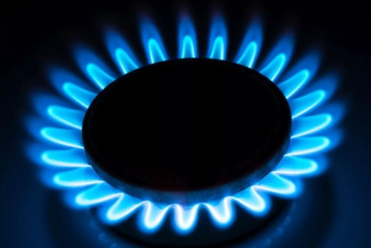 burning gas stove hob blue flames close up in the dark on a black background