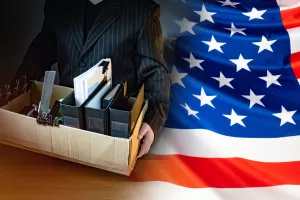 Unemployed. Man holds a box with personal belongings. USA flag. Concept - unemployed American. American was fired. USA resident is unemployed. Stationery in a cardboard box. American labor market amerikasad, zaposlenost, stopa zaposlenosti, posao, poslovi