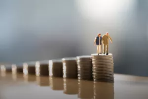Concept of retirement planning. Miniature people: Old couple figure standing on top of coin stack.mirovinski fondovi