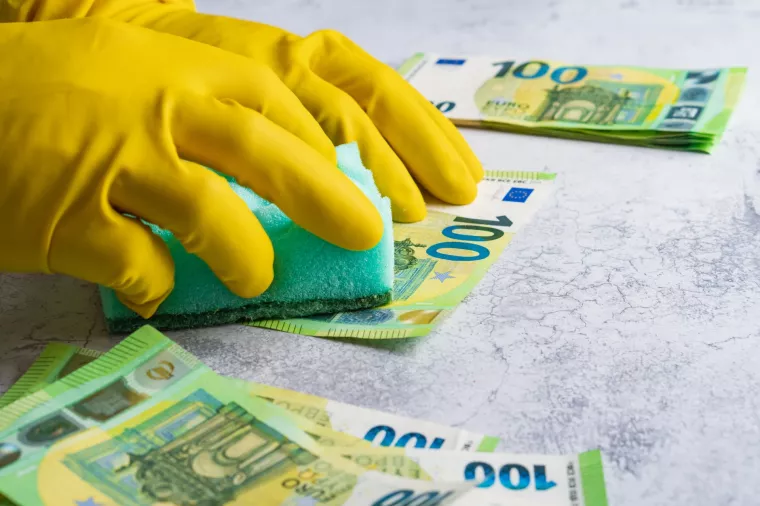 Pranje novca - ilustracijaLaundering of money. Man in yellow gloves washes papper hundred 100 euro with green washcloth