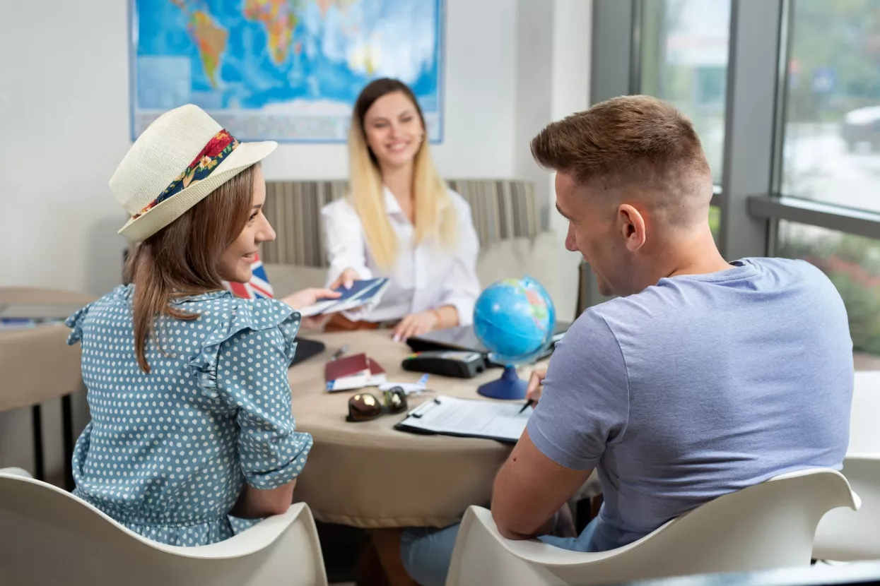 Woman travel agent gives a couple passports with plane tickets in travel agency.
